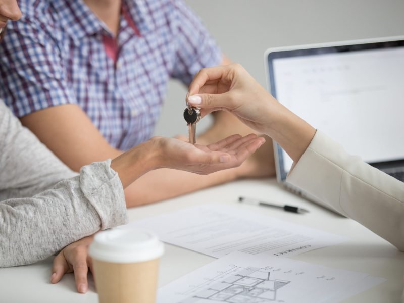 Buying new house concept, realtor giving keys to happy couple customers renters owners making real estate rent purchase deal, property ownership, mortgage loan investment contract, close up view