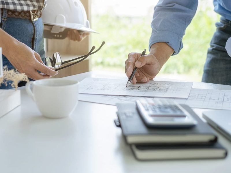 Engineer or architect teamwork working on construction project with building model and blueprint in office. Construction concept.